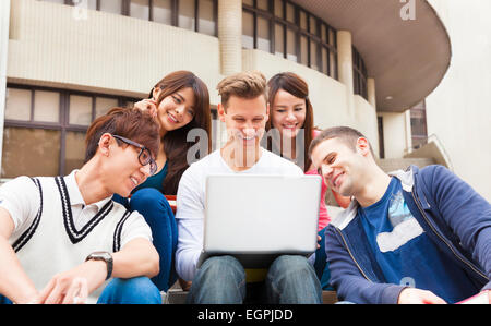 Glückliche junge Gruppe von Studenten, die gerade des Laptops Stockfoto