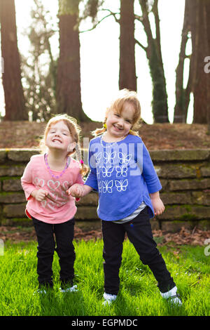 Lifestyle Portrait von identischen Zwillingsschwestern an einem Park interagieren und gemeinsam Spaß haben. Stockfoto