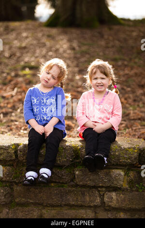 Lifestyle Portrait von identischen Zwillingsschwestern an einem Park interagieren und gemeinsam Spaß haben. Stockfoto