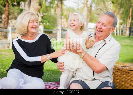 Liebevolle Enkelin und Großeltern spielen draußen im Park. Stockfoto