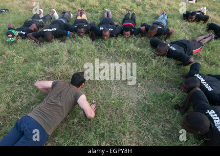 Der Leiter der Einav Levy-Delegation von Natan International Humanitarian Aid nahm an einer körperlichen Übung mit einer Gruppe haitianischer Männer Teil, die als Sicherheitsbeamte des provisorischen Lagers für Überlebende eines Erdbebens der Stärke 7,0 ausgebildet wurden, das Haiti am 12. Januar 2010 am Stadtrand von Port-au-Prince heimsuchte Stockfoto