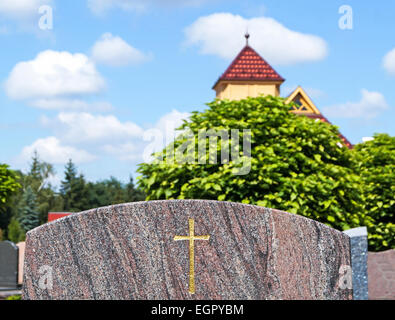 Grabstein auf dem Friedhof, im Hintergrund ist eine kleine Kapelle Stockfoto