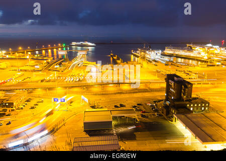 Nachtaufnahme mit der Morgendämmerung, die gerade am beleuchteten Autofähre-Terminal am englischen Kanalhafen Dover beginnt. Blick auf den Hafen. Stockfoto