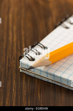 Bleistift und aufgegebenen Notebook auf hölzernen Hintergrund Stockfoto