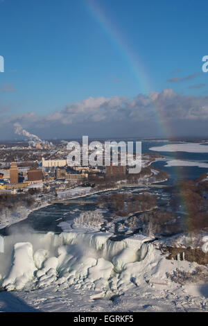 Niagara Falls, Ontario - Niagara Falls im Winter. Unter einem Regenbogen ist die American Falls stark im Eis überzogen. Stockfoto