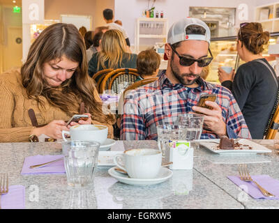 Ein paar ist ganz konzentriert auf die Überprüfung ihres Handys nach einer Mahlzeit in einem in Santa Barbara, Kalifornien. Stockfoto