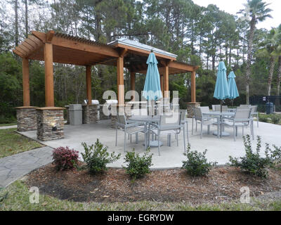 Patio-Möbel mit Sonnenschirmen auf steinernen Terrasse in der Nähe von gehobenen Eigentumswohnung Gebäude - Barbecue-Bereich-Stil in Florida Stockfoto