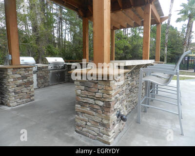 Patio-Möbel mit Sonnenschirmen auf steinernen Terrasse in der Nähe von gehobenen Eigentumswohnung Gebäude - Barbecue-Bereich-Stil in Florida - Nahaufnahme Stockfoto