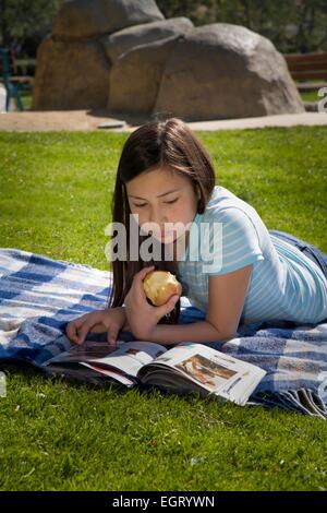 12 -13 Jahre alten gemischten Rennen Vietnamesische/Kaukasische Mädchen lesen Magazin auf Gras Park junger Mensch Menschen Tween tweens HERR © Myrleen Pearson Stockfoto