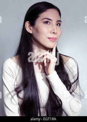 Schönheit-Porträt einer jungen japanischen Frau mit langen schwarzen Haaren auf grauem Hintergrund isoliert Stockfoto