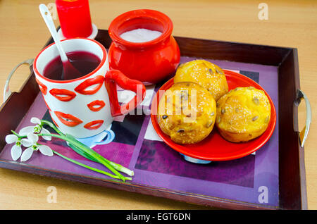 Mais-Brot mit Sesam, Team in einem Lip gemusterten Becher, Zucker und Schneeglöckchen auf einem Tablett, machen ein romantisches Frühstück im Bett Stockfoto