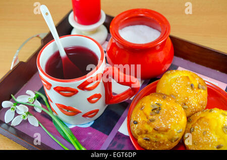 Mais-Brot mit Sesam, Team in einem Lip gemusterten Becher, Zucker und Schneeglöckchen auf einem Tablett, machen ein romantisches Frühstück im Bett Stockfoto