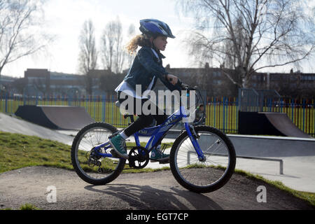 Sieben Jahre altes Mädchen tragen einen Helm Radfahren rund um ein BMX-Bike-Strecke an einem kalten Wintertag in London Stockfoto