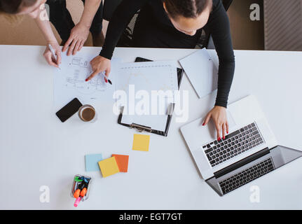 Business-Team arbeitet an einem neuen Plan mit Laptop. Draufsicht auf zwei junge Frauen in Führungspositionen arbeiten zusammen mit Laptop und unter Stockfoto