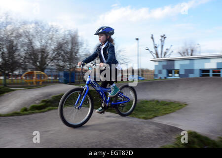 Sieben Jahre altes Mädchen tragen einen Helm Radfahren rund um ein BMX-Bike-Strecke an einem kalten Wintertag in London Stockfoto