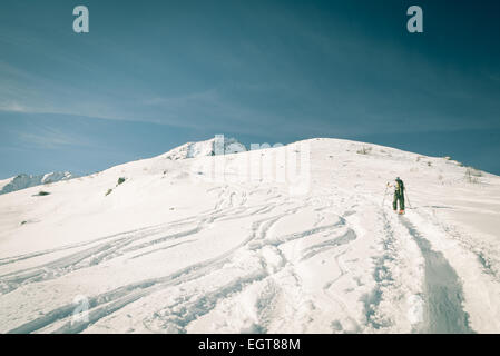 Tour-Skifahrer Wandern bergauf in malerischen schneebedeckten Kulisse unter strahlender Sonne in den italienischen Alpen. Kreuz verarbeitet zu Retro-altmodische Stockfoto