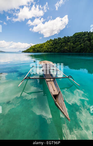 Traditionelles Boot schwimmt auf den transparenten blau getönten des entfernten Togean (oder Togian) Laguneninseln, Sulawesi, Indonesien Stockfoto
