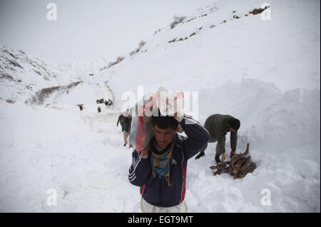 Panjshir, Afghanistan. 1. März 2015. Afghanischen Männer tragen Holz gegenüber ihren zerstörten Häusern nach Lawinen in Abdullah Khil von Panjshir Provinz, Afghanistan, 1. März 2015. Afghanische Regierung und Hilfe Agenturen haben verstärkt Bemühungen um die Soforthilfe für die Opfer der tödliche Lawinen in Panjshir Ostprovinz. © Ahmad Massoud/Xinhua/Alamy Live-Nachrichten Stockfoto