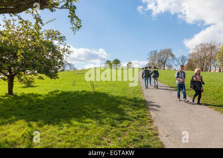 Menschen zu Fuß nach oben und unten einen Hügel in einem Park an einem sonnigen Tag im Frühling. Primrose Hill, London, England, Großbritannien Stockfoto