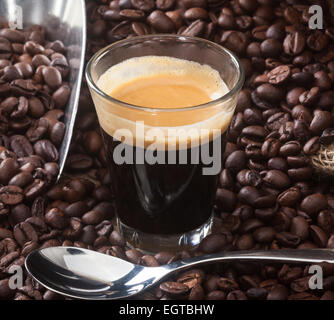 Espresso Kaffee in Glastasse mit Kaffeebohnen auf Holztisch. Stockfoto