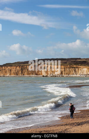 Eine Frau bereitet zu paddeln im Meer an einem Wintertag auf dem Kiesstrand im Cuckmere Haven. Stockfoto