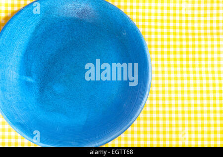 Closeup, blaue Platte auf gelb karierte Tischdecke Stockfoto