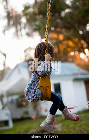 Eine Mädchen sitzt auf einer Schaukel Garten. Stockfoto