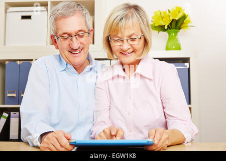 Lächelnd älteres Paar mit Tablet-Computer gemeinsam im Internet surfen Stockfoto