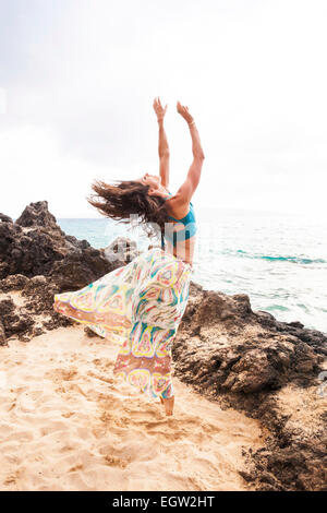 Frau, tanzen und springen am Strand. Stockfoto
