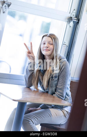 Porträt von Tween/Teen in Jean Jacke geben Frieden Finger. Stockfoto