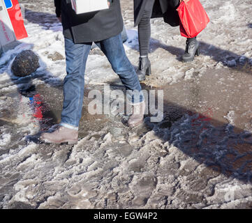 Fußgänger slog durch Pfützen, Matsch und Schnee an Straßenkreuzungen mit Schnee dam verstopfte Abflüsse im Stadtteil Lower East Side von New York auf Sonntag, 22. Februar 2015.  (© Richard B. Levine) Stockfoto