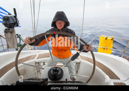 Junger Mann Skipper im Meer an der Spitze einer Segelyacht. Stockfoto