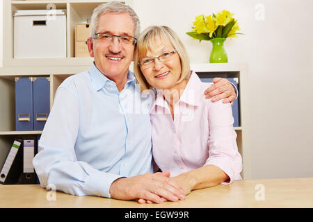 Glückliche alte senior paar zu Hause an einem Tisch sitzen Stockfoto