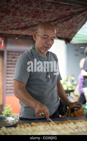 Eine DSLR Bild von einem Lebensmittel Standinhaber Grillen Bananen auf einer Straße im Talat Phlu, Bangkok, Thailand. Stockfoto