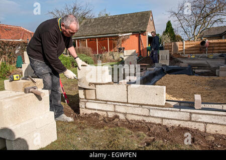 Maurer trimmen überschüssigen Mörtel Zement während eine Breezeblock Betonklotz Mauer auf einem britischen home Improvement Projekt bauen. Stockfoto