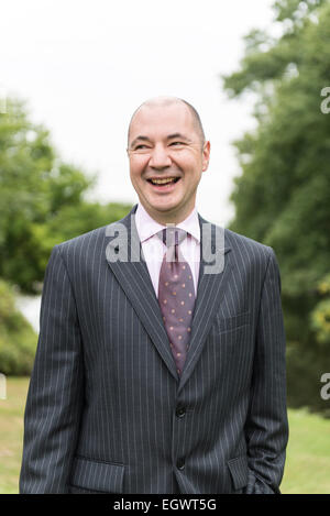 eine professionelle Geschäftsmann / Hotelmanager steht in den Gärten von einer englischen Landhaushotel in einem Business-Anzug Stockfoto