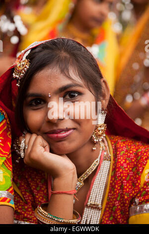 Junge Frau in ihrer typischen farbenfrohen Tracht auf dem Kamel Messe Pushkar Mela, Pushkar, Rajasthan, Indien, Asien Stockfoto