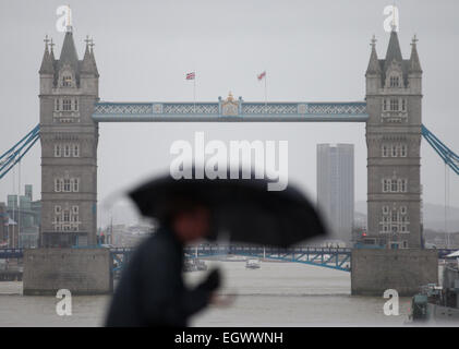 Vereinigtes Königreich, London: Ein Mann kämpft gegen die starken Winden mit ihrem Schirm als er über eine Brücke im Zentrum von London am 12. Februar 2014 geht. Stockfoto