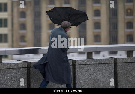 Vereinigtes Königreich, London: Ein Mann kämpft gegen die starken Winden mit ihrem Schirm als er über eine Brücke im Zentrum von London am 12. Februar 2014 geht. Stockfoto