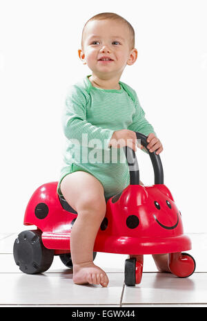 Baby Boy (12,5 Monate) sitzt auf einer Fahrt mit Marienkäfer Spielzeug Stockfoto