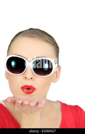 Frau mit Sonnenbrille weht Küsse auf weißem Hintergrund Stockfoto