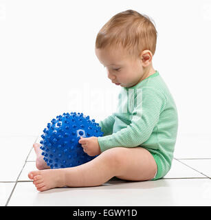 Baby Boy (12,5 Monate) sitzen hält eine holprige Ball Spielzeug Stockfoto