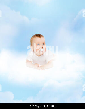 lächelnden Baby liegend auf Wolke mit Dummy in Mund Stockfoto