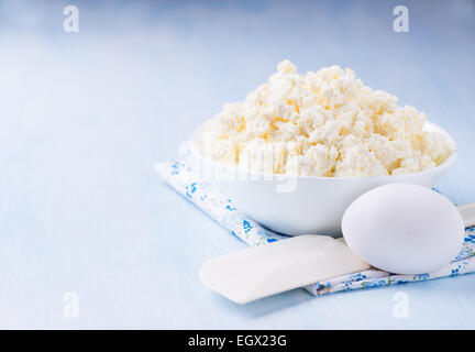 Hüttenkäse in weiße Schüssel über hellblauen Hintergrund, selektiven Fokus Stockfoto