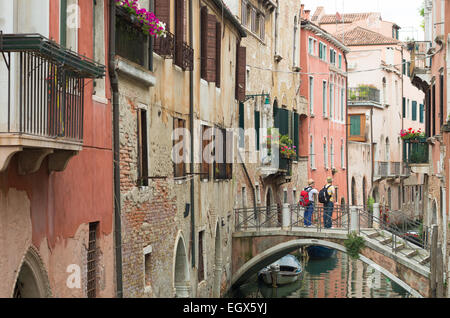 zwei unbekannte Touristen auf einer kleinen Brücke über einen Kanal in Venedig, Italien Stockfoto