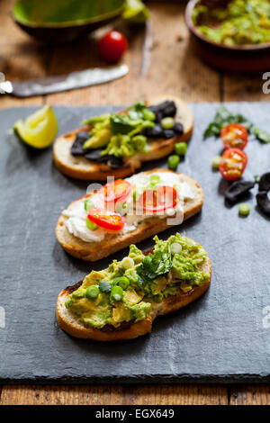 Kanapees mit Avocado zu verbreiten, Ziegenkäse und schwarzem Knoblauch Stockfoto