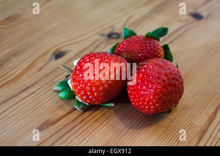 3 Erdbeeren auf einem Holztisch liegend Stockfoto