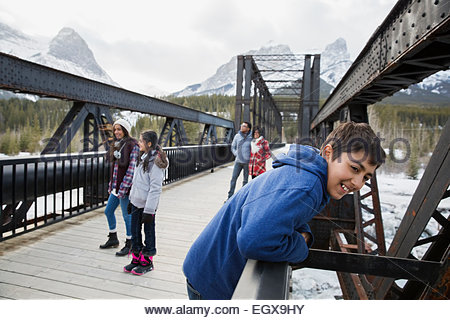 Familie auf der Brücke unter verschneiten Bergen