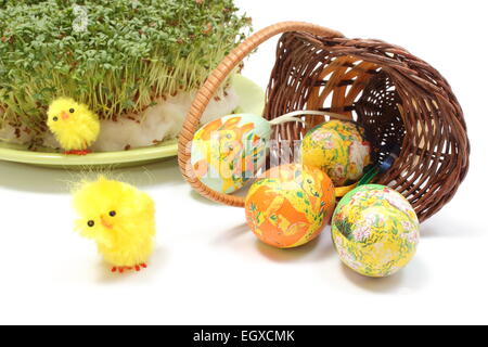 Nahaufnahme der lustige Ostern Huhn, bunt bemalte Ostereier in umgestürzten Weidenkorb und frische grüne Kuckuck-Blume, Stockfoto