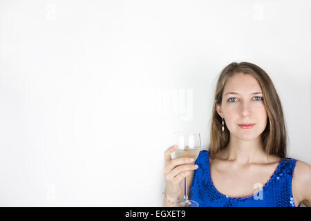 Hübsche junge Frau trägt blau Paillettenkleid und halten Glas Weißwein Stockfoto